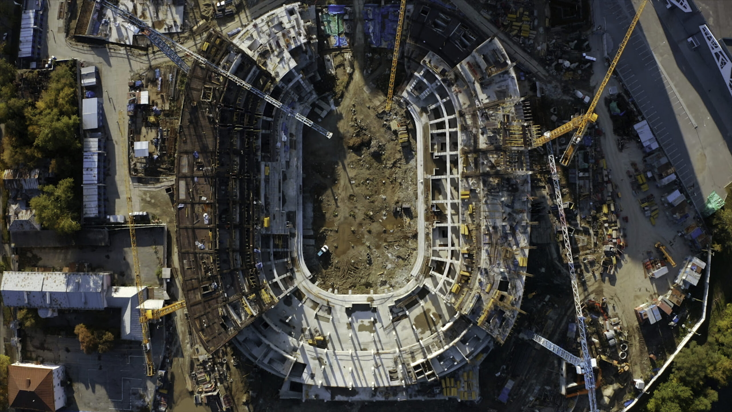 Home top view of stadium construction in city. stock footage. construction of modern sports stadium. cranes on construction site with oval stadium